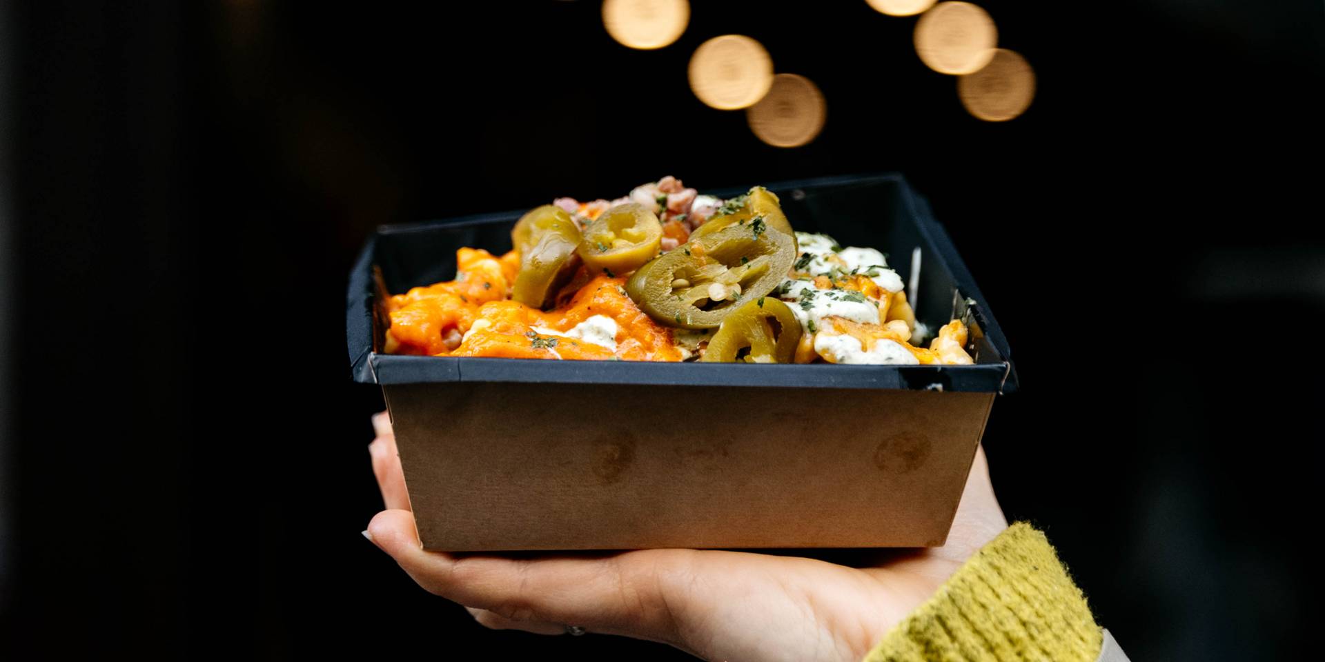 Nokedlish signature dish held up against golden bokeh lights